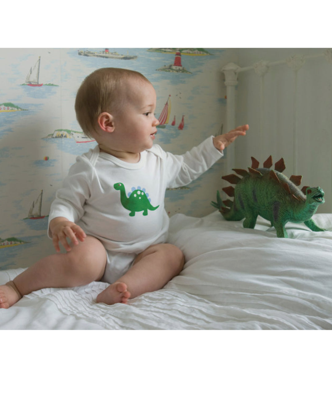 Baby mit weißem Body mit grünem Saurier