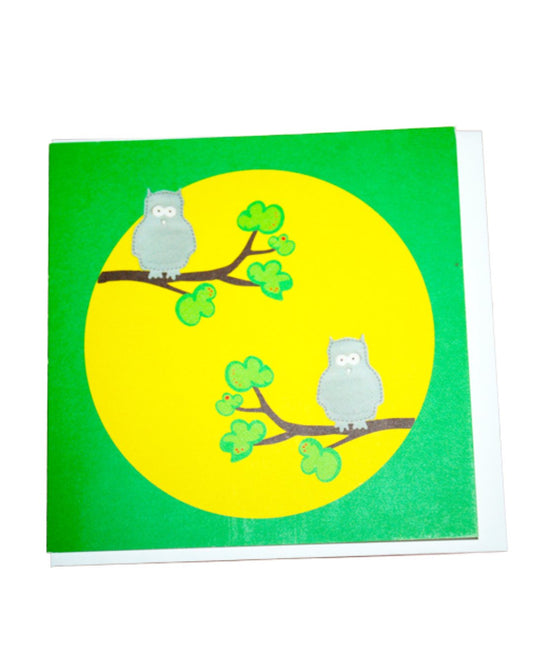 Grüne Glückwunschkarte mit großem gelben Punkt und zwei grauen Eulen auf Zweigen sitzend